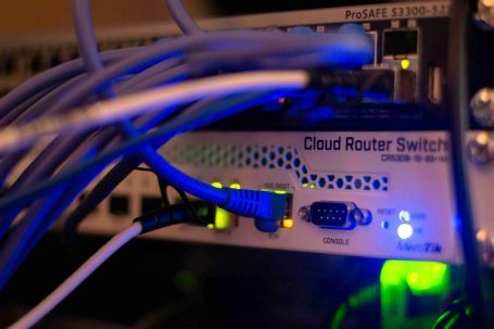 Nahaufnahme eines Cloud-Router-Switch mit blauen und grünen LED-Anzeigen und Kabeln.
